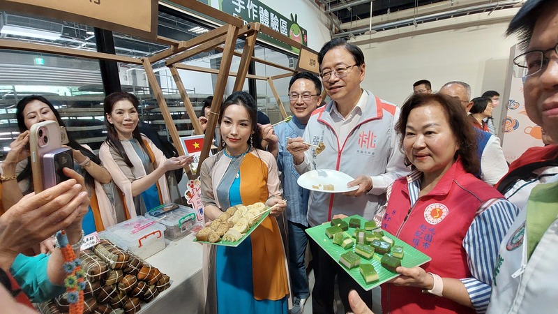 桃園市長與各國新住民攤位主合影並試吃越南與印尼特色美食，展現端午節活動的多元文化與傳統服飾魅力。
