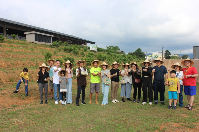 臺灣客家茶文化館茉莉花茶DIY體驗，親子家庭與參與者於桃園龍潭茶園合影留念，戴著斗笠手持窨花茶成品，展現歡樂茶文化手作氛圍。