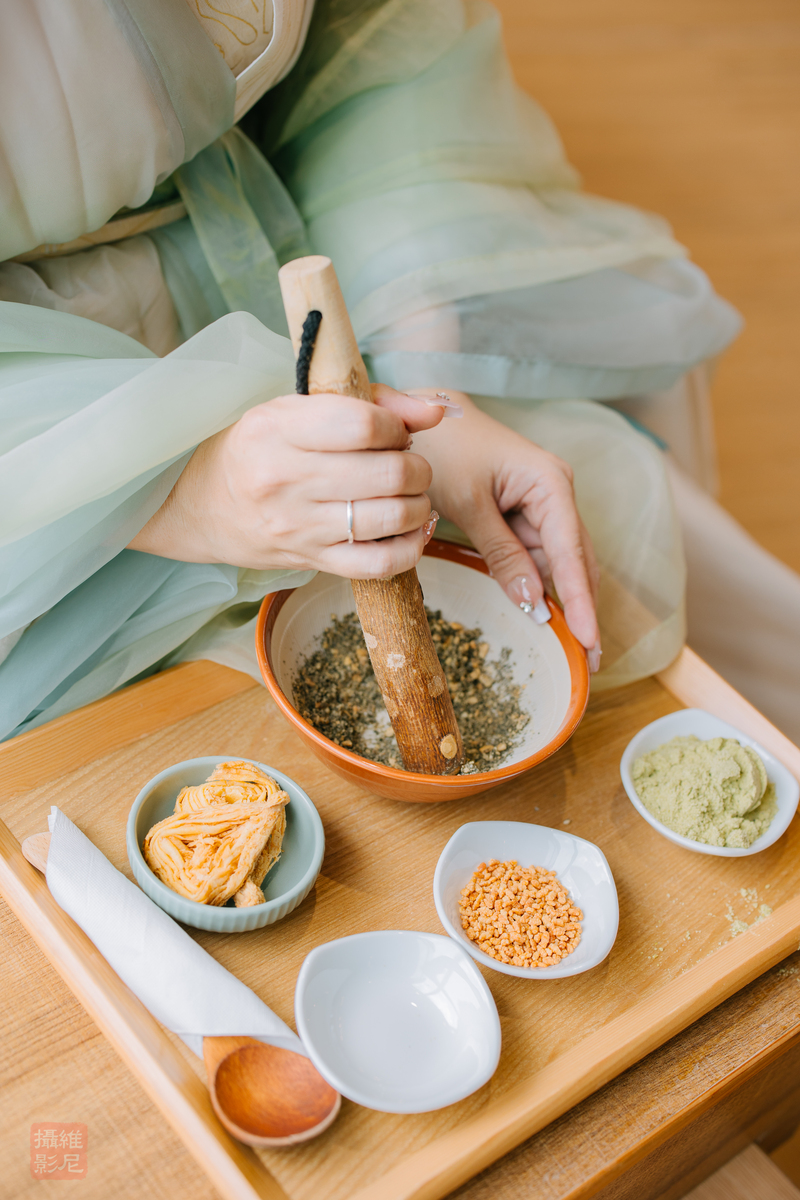 台灣客家茶文化館的擂茶體驗，一位女生正體驗著擂茶體驗，客茶館延伸客茶館的硬頸精神，研發出擂茶領導學課程，為企業建構領導力與團結力。