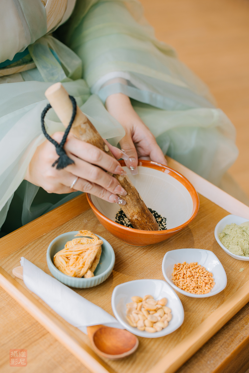 客家擂茶體驗活動，參加者穿著傳統服飾以木杵研磨芝麻與茶粉，搭配花生、米香與茶點食材，展現台灣傳統客家茶文化